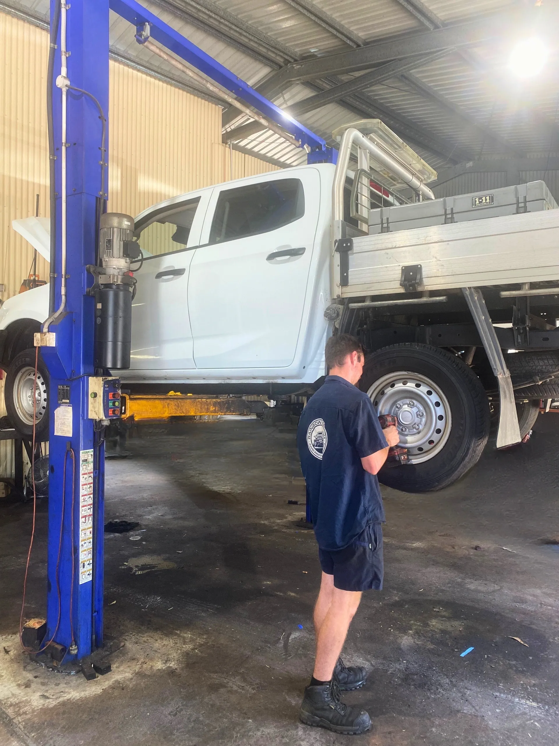 Rainbow Beach mechanic carrying out a logbook service on a ute raised on the workshop hoist